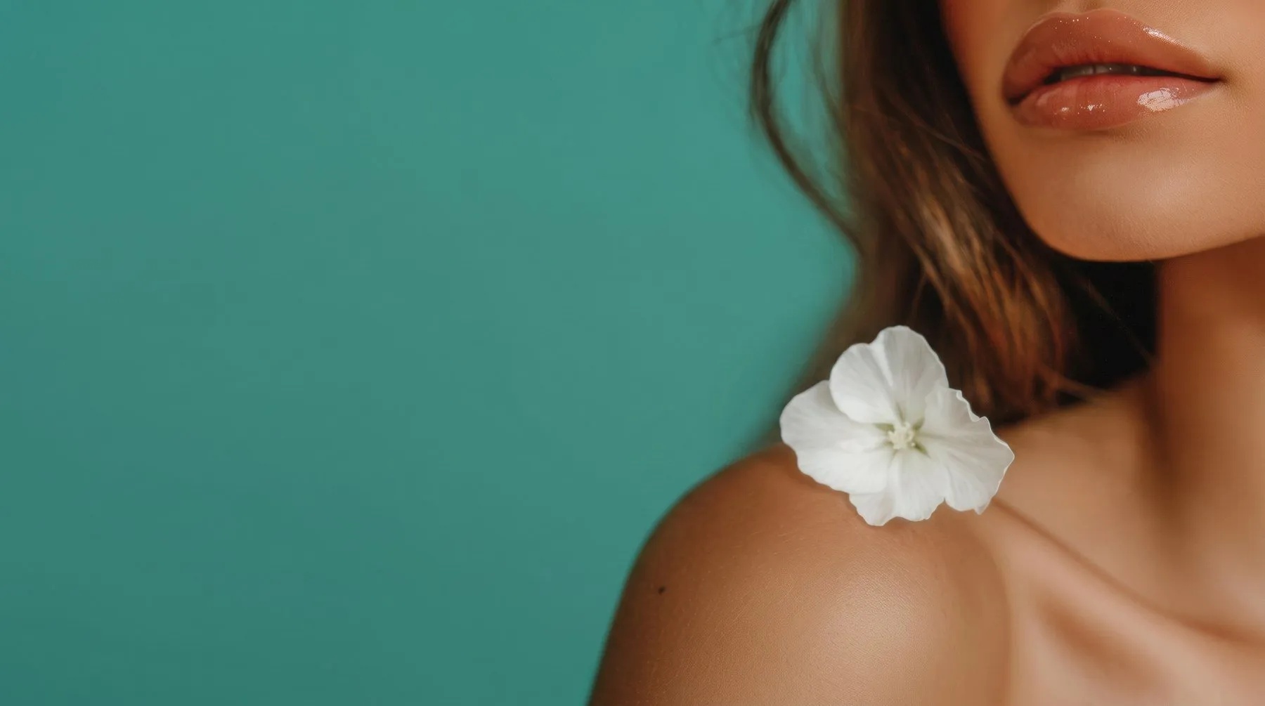 Detalhe de rosto feminino com uma flor branca no ombro